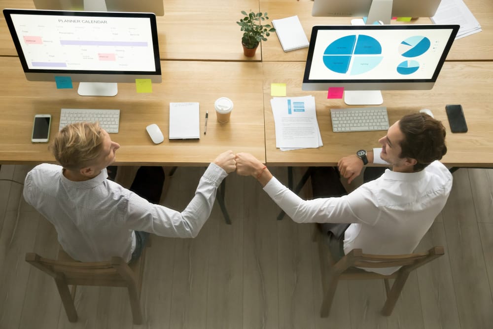 Smiling colleagues fist bumping celebrating successful corporate teamwork